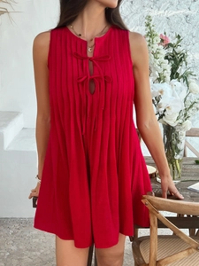 Detail of red sleeveless pleated mini dress featuring a self-tie bow at the neckline