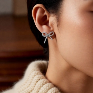 Close-up of elegant bow-shaped silver clip-on earring with sparkling zircon paving