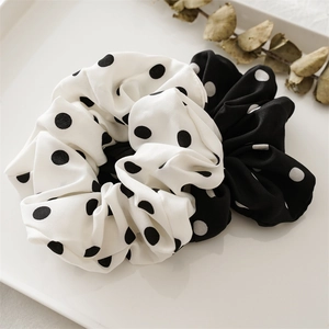 Close-up of black and white polka dot satin scrunchies with elegant ribbon bows