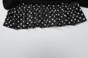 Détail de l'ourlet de la jupe à pois noirs et blancs avec bord à volants et tissu doux