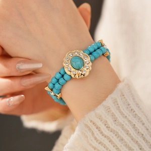 Gros plan détaillé d'un bracelet à double rangée de perles turquoise avec strass dorés