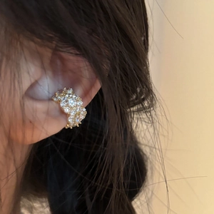 Detailed side view of a gold-layered ear cuff with white zircon stones worn on the ear