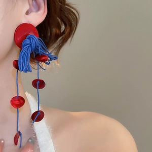 Detail of bohemian long tassel earrings with red resin disks and navy blue fiber fringe