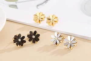 Detailed view of daisy-shaped stud earrings in gold and two-tone polished metal finishes