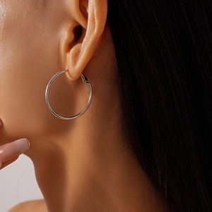 Close-up of minimalist silver geometric hoop earrings worn by a model for size and style