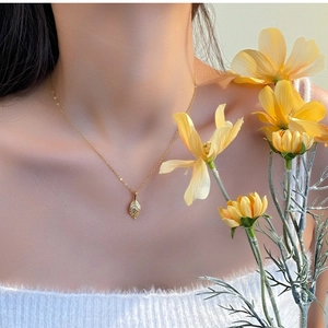Detailed view of a gold leaf pendant necklace with intricate veins on a female model