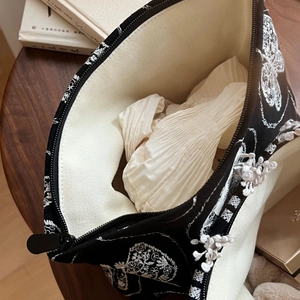 Détail de la broderie florale blanche sur un sac en toile noire avec fermeture éclair élégante