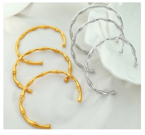 Detailed close-up of bamboo-style 18K gold and silver bangles on white ceramic