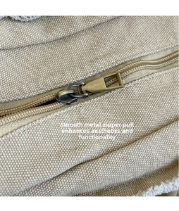 Detailed close-up of the vintage bronze zipper on high-quality beige canvas tote bag