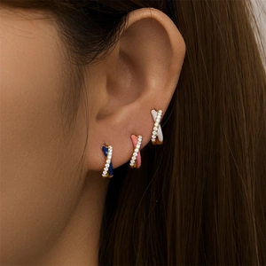 Detail of colorful enamel cross hoop earrings with cubic zirconia on a model's ear