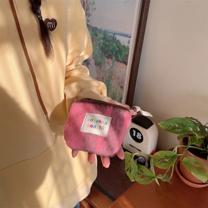 Close-up of mini pink and purple checkered plush makeup pouch with zipper closure