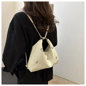 Dettaglio della borsa tote in pelle goffrata bianco crema con ornamento a farfalla in metallo