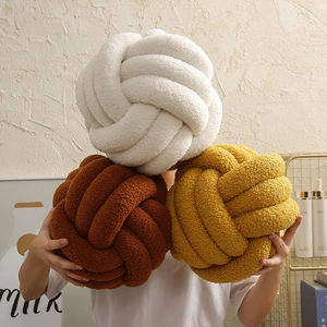 Handmade knotted ball pillows in white, brown, and mustard yellow plush fabric
