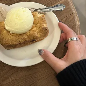 Close-up of vintage silver heart and flower engraved ring on hand in a cozy cafe setting