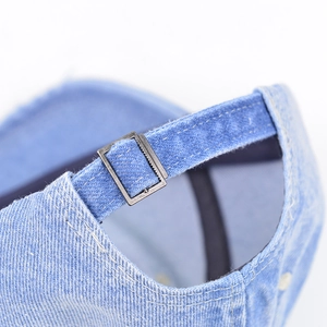 Detailed macro view of vintage washed blue denim cap with adjustable brass buckle strap