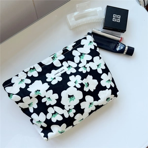 Detail of floral print cotton makeup bag with zip closure and simple wish woven label