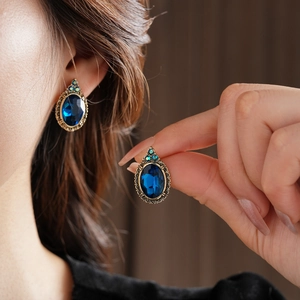 Détail de boucles d'oreilles vintage avec pierre ovale bleu foncé et motifs floraux