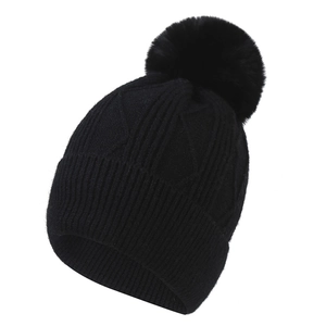 Détail du bonnet d'hiver noir en maille torsadée avec grand pompon en fausse fourrure