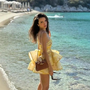 Sexy one-shoulder yellow floral tiered dress with waist cutout on a sunny beach