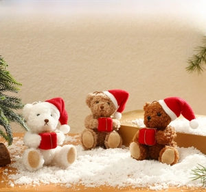 Three plush Christmas bears in white and brown with red hats on snowy background
