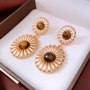 Detailed view of vintage gold hollow oval earrings with tiger eye stone in a jewelry box
