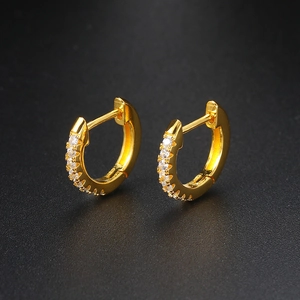 Detail of golden huggie hoop earrings with micro-paved white zircons on black background