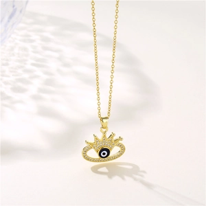 Golden crown evil eye necklace with blue zircon crystals on white background