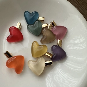 Close-up of colorful heart hair clips with opal texture in a white ceramic bowl