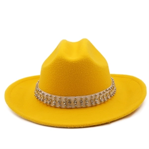 Detail of yellow wool fedora hat with studded rhinestone trim on a white background