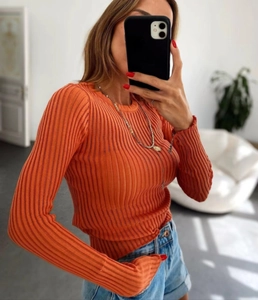 Detail of slim-fit orange ribbed knit sweater with round neck and long sleeves