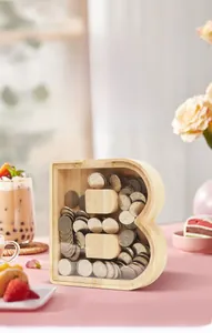 Detail view of B-shaped wooden letter piggy bank with a transparent acrylic front panel