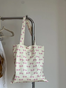 Détail du sac cabas en toile blanc cassé avec motifs nœuds roses et bandoulière suspendu