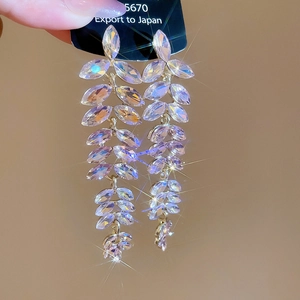 Macro shot of shimmering crystal leaf tassel earrings with sparkling star filter effects