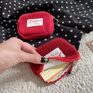 Close-up of red corduroy and fuzzy small coin purses with metal zippers for storage