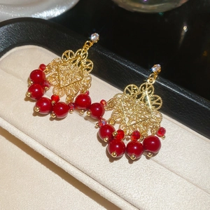 Detail of vintage gold hollow earrings featuring red tiger eye beads and crystals