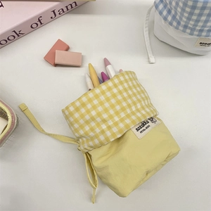Detailed view of yellow drawstring stationery pouch with plaid trim holding pencils