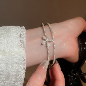 Close-up of a double-layered gold bracelet featuring a zircon flower and pave-set crystals