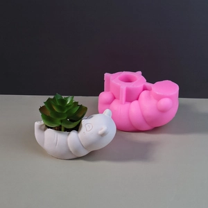 Pink silicone mold next to a finished white cartoon bear succulent planter