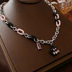 Close-up of pink crystal pendant and black cartoon cat charm on silver chain