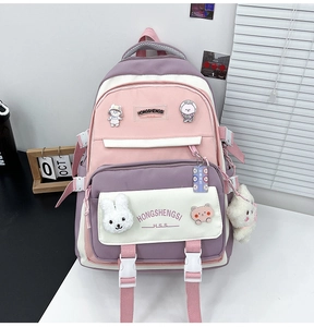 Detail of multi-compartment school backpack with cute pins and plush rabbit pendant