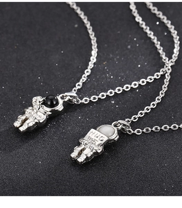 Macro shot of couple's astronaut pendants with Hug Me engraving on silver steel O-chains