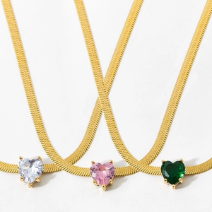 Golden snake chain necklace with heart emerald and pink zircon pendant on white background