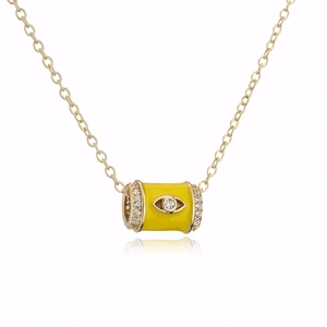 Macro detail of 18K gold-plated cylinder pendant featuring yellow enamel and evil eye zircon