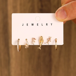 Detail of gold piercing set featuring mermaid stud and marquise cubic zirconia on card