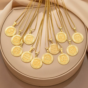 Pendentifs zodiaque dorés polis présentés sur un support rond de couleur beige