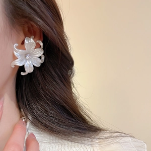 Detailed close-up of a large white iridescent floral stud earring with a center zircon