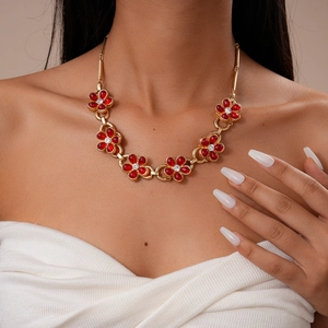 Detailed close-up of vintage golden necklace with red flower petals and crystal centers