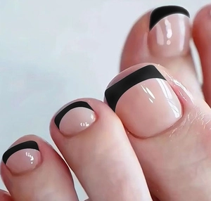 Dettaglio delle unghie dei piedi nude con linee nere in stile french minimalista