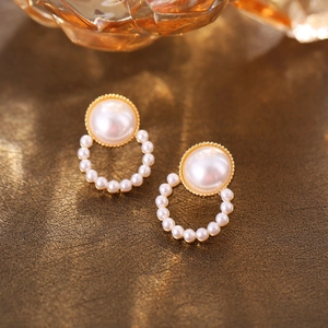 Detailed close-up of retro pearl stud earrings with textured gold-plated edges