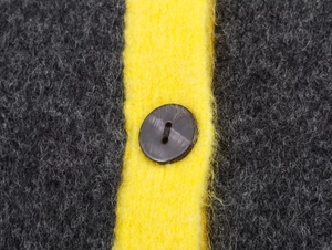 Detailed macro view of plush grey and yellow striped wool fabric with a brown button